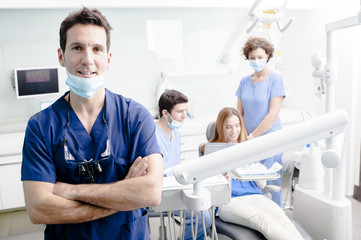 Een portret van een tandarts met zijn team op de achtergrond