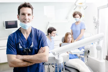 Fotobehang Tandarts Een portret van een tandarts met zijn team op de achtergrond