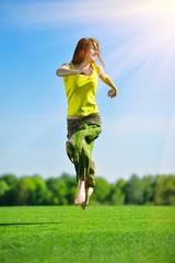 Fototapeta na wymiar Young woman running on a green meadow