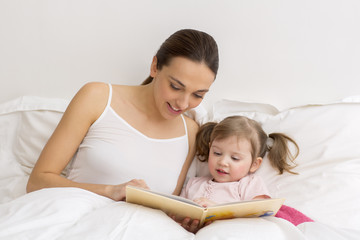 Child reading a book with her mother