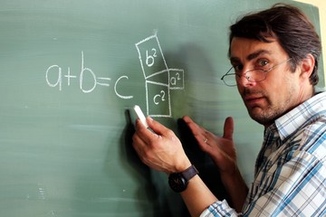 Lehrer mit Brille an Tafel erklärt Mathematikformel