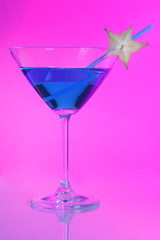 Blue cocktail in martini glass on pink background