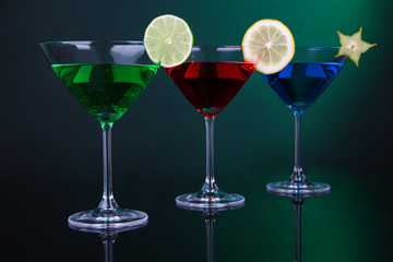 Alcoholic cocktails in martini glasses on dark green background