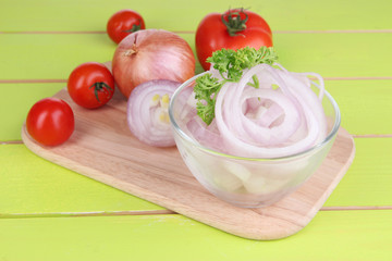 Onion cut with rings in bowl on wooden table close-up