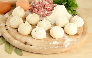 Raw dumplings and ingredients on wooden table