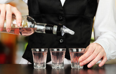 Barmen hand with bottle  pouring beverage into glasses,