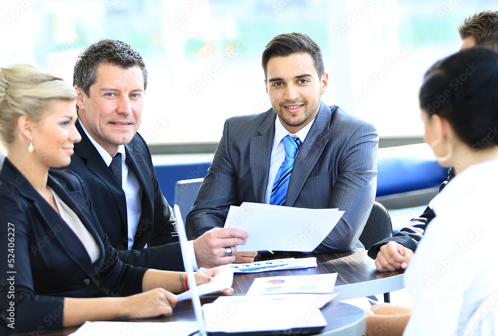 Wall mural Smiling young man sitting at a business meeting with colleagues