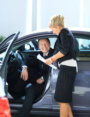 Man buying a car in dealership sitting in his new auto