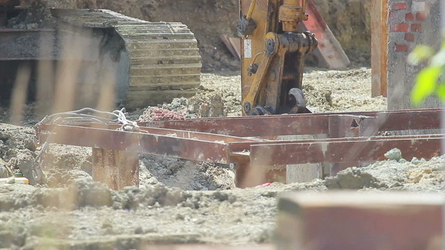 Construction extravator diggin in the ground. People in the shot