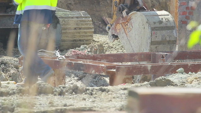 Construction extravator diggin in the ground. People in the shot