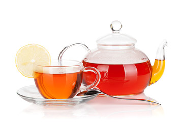Glass cup with lemon slice and teapot of black tea