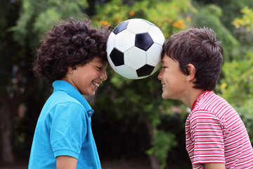 Two young boys playng with a soccer ball - close view