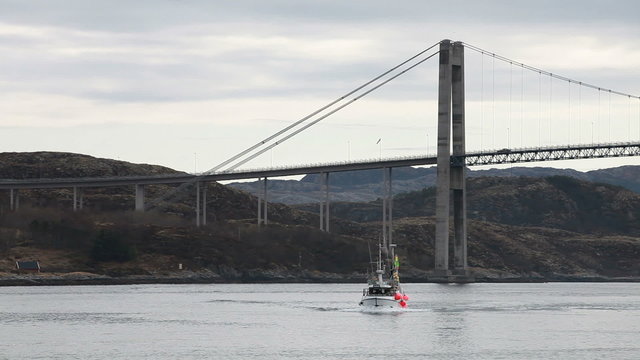 Small fishing Norwegian boat goes on still sea water
