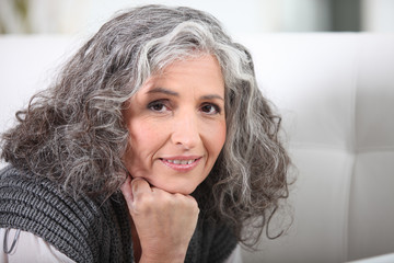 Grey-haired woman resting chin on hand