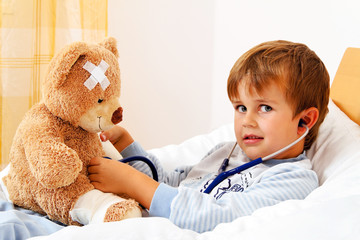 Krankes Kind untersucht Teddy mit Stethoskop