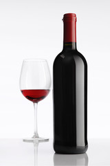 glass with red wine bottle on white background