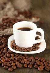 Cup of coffee and coffee beans on wooden background