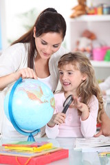 Fototapeta premium Mother and daughter looking at a globe with a magnifying glass