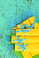 Blue plastic forks wrapped in yellow paper napkins,