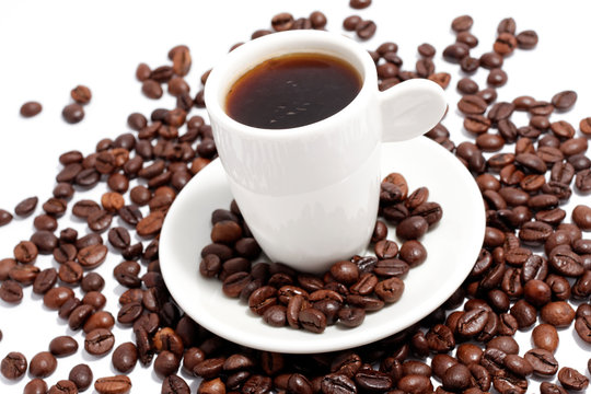a cup of espresso with coffee beans on white