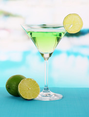 Green cocktail with lime on table on bright background