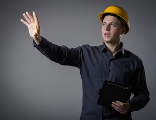 young builder in a building helmet with a notebook in hands
