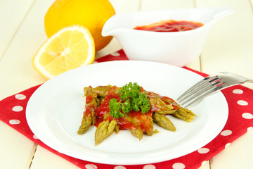Asparagus on plate, on wooden background