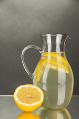 Lemonade in pitcher on grey background