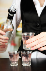 Barmen hand with bottle  pouring beverage into glasses,