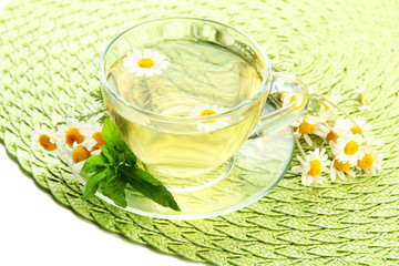 Cup of herbal tea with wild camomiles and mint, isolated