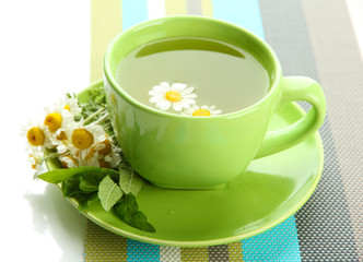 Cup of herbal tea with wild camomiles and mint, isolated
