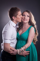 Image of man kissing cheerful pregnant woman