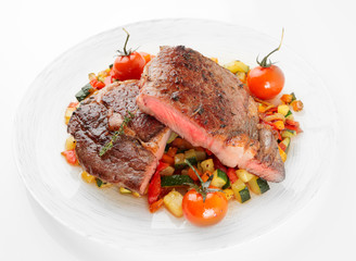 Medium fried steak with vegetables shot on light background