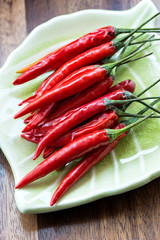 Red chili peppers on plate on wooden background