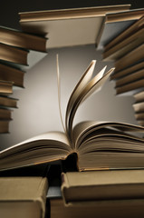 Stacks of old books with one opened among them
