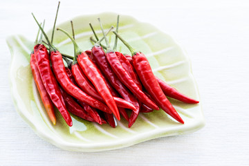 Red chili peppers on plate over light background