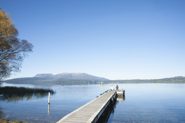 Jetty on Lake tarawera, with couple seated in distance.