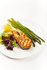 Grilled salmon steak with asparagus, lemon and salad
