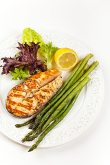 Grilled salmon steak with asparagus, lemon and salad