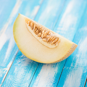 Slice of a ripe Galia melon on wooden boards, close-up