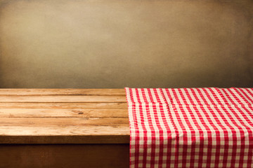 Empty wooden table covered with red checked tablecloth