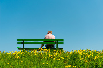Mann auf grüner Bank im Frühling 2017