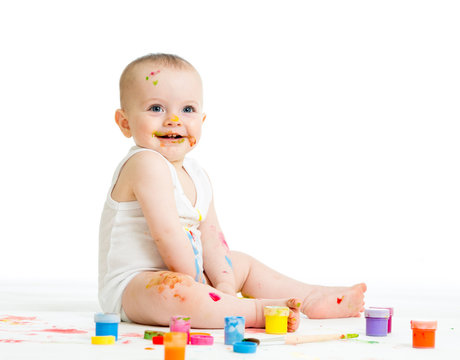 smiling baby drawing with a finger's paints