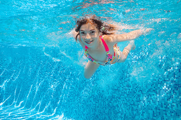 Happy active child swims underwater in pool