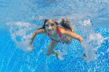 Happy active child swims underwater in pool