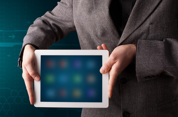 Businessman holding a white modern tablet with blurry apps