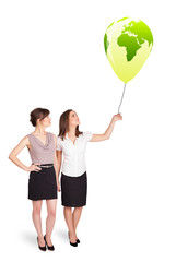 Happy ladies holding a green globe balloon