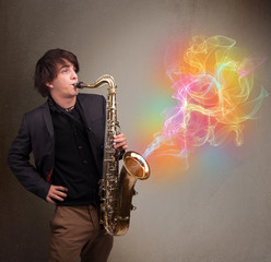 Fototapeta na wymiar Attractive musician playing on saxophone with colorful abstract