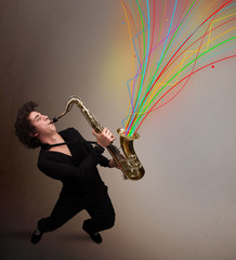 Attractive musician playing on saxophone while colorful abstract