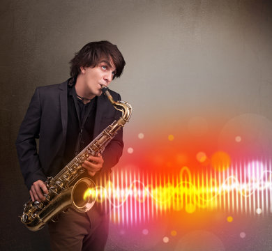 Young man playing on saxophone with colorful sound waves